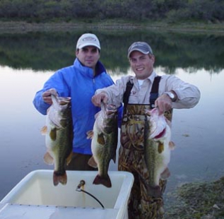 Derek Stratton and Bradford Bryant hold 3 nice bass being transferred from the large lake to the small lake at San Saba Waco Creek Ranch